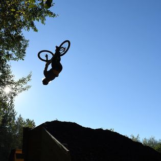 Siluett mot himlen av en kvinna som hoppar med mountainbike i Mountainbikeskolans bikepark.