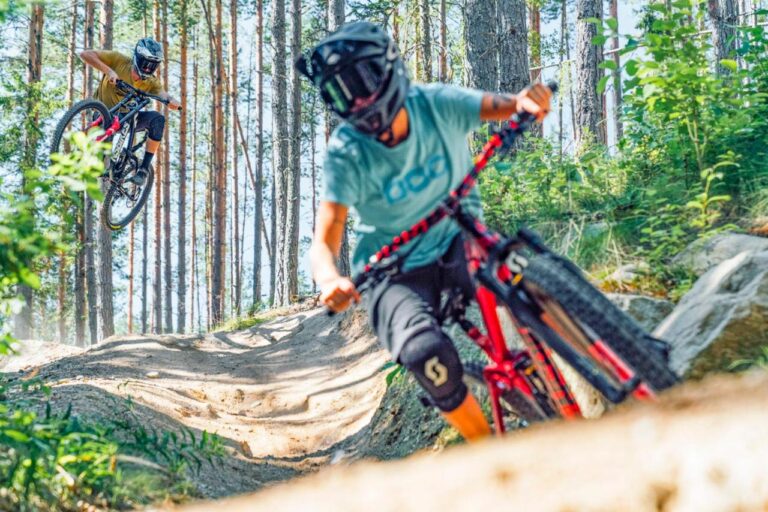 Två ungdomar åker enduro på mountainbike på en bana i skogen